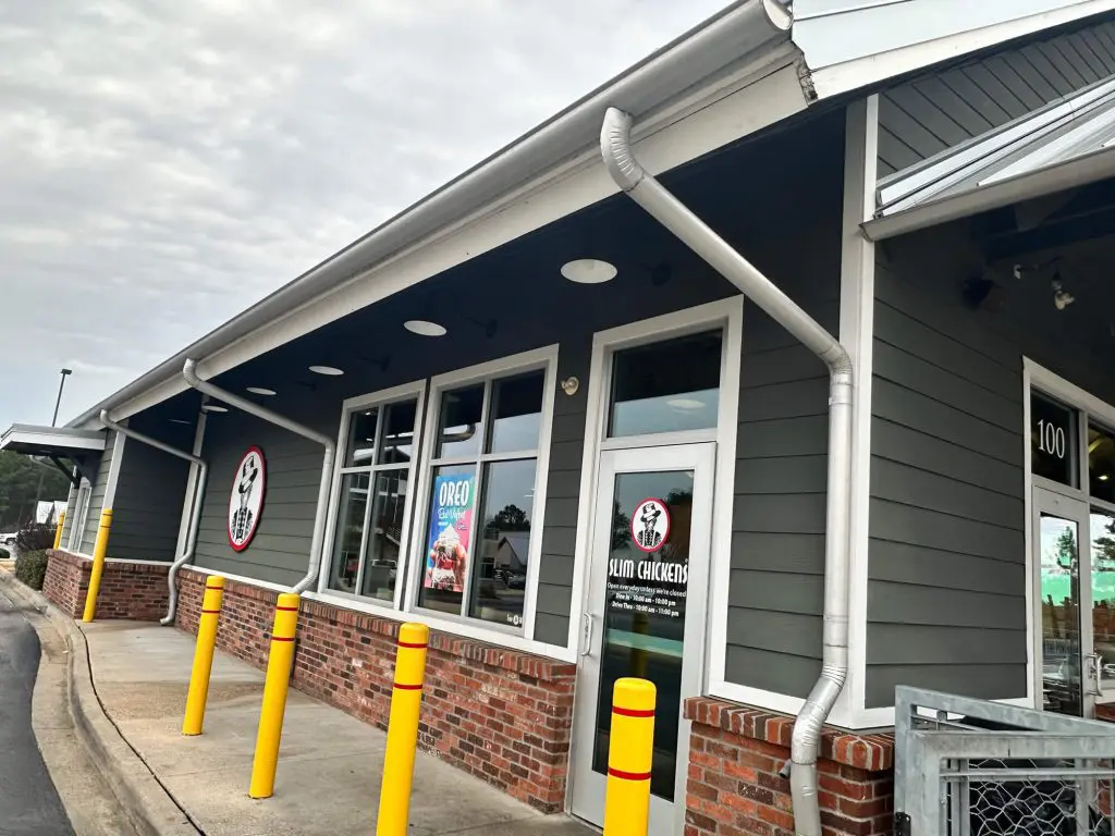 Expert commercial exterior painting for the Slim Chickens restaurant, featuring modern dark gray siding, white trim, and red brick accents in the Tyler, TX area.