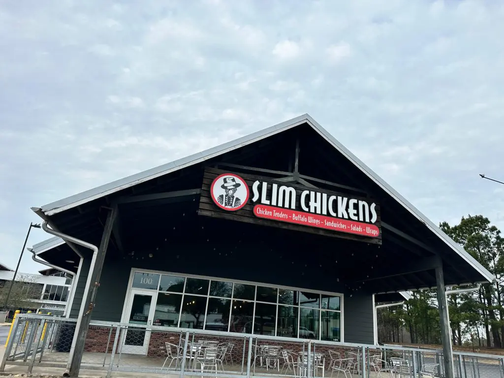 Expert commercial exterior painting of the Slim Chickens restaurant facade, featuring modern dark gray siding, white trim, and a metal roof in the Tyler, TX area.