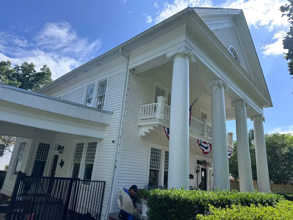 Expert exterior house painting and trim work on a large, classic white residential home with stately columns and detailed architecture in the Tyler, TX area.