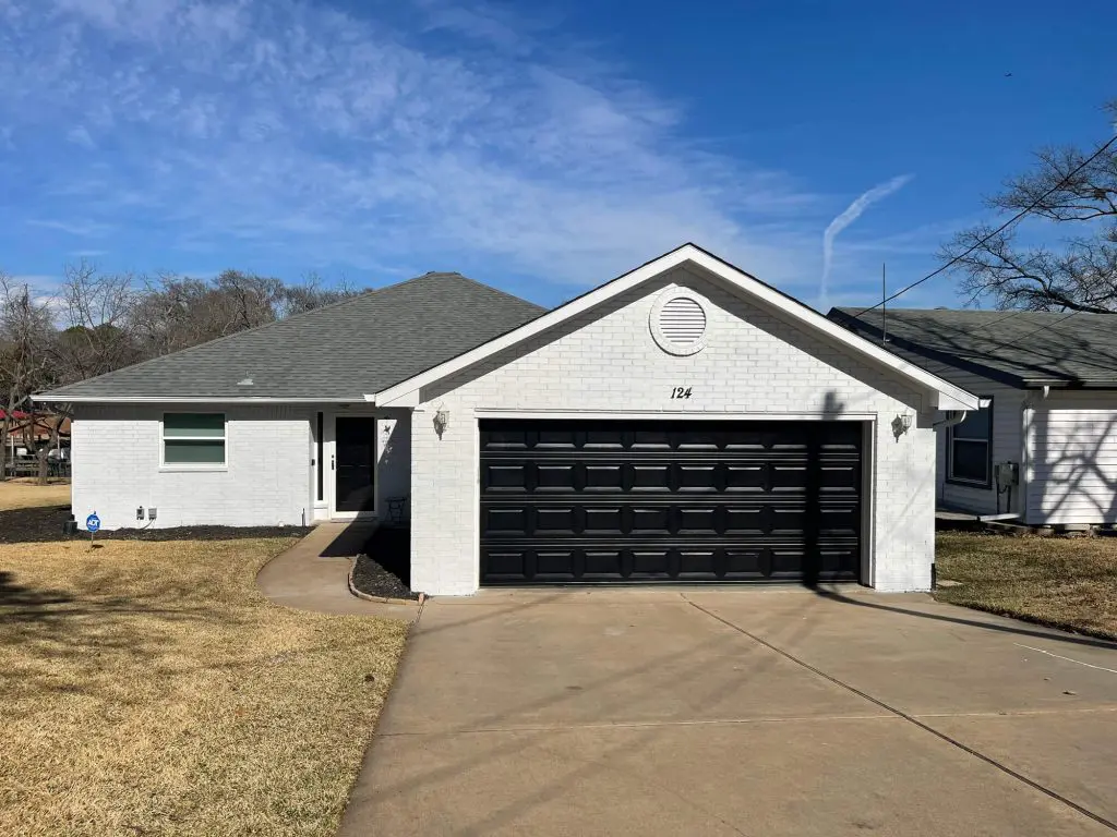 Expert exterior painting transforming a home with custom white painted brick and a contrasting matte black garage door in the Tyler, TX area.