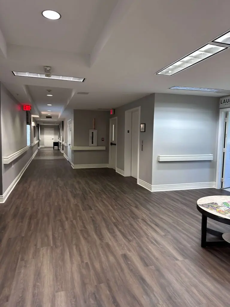 Expert commercial interior painting in a medical or institutional facility hallway, featuring professional light gray walls and white handrails in the Tyler, TX area.