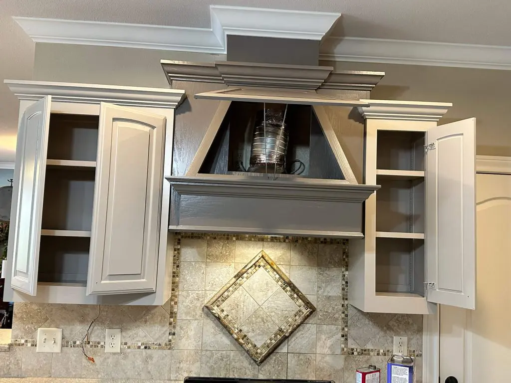 High-quality custom cabinet and detailed range hood refinishing featuring a smooth gray paint finish and crown molding accents.