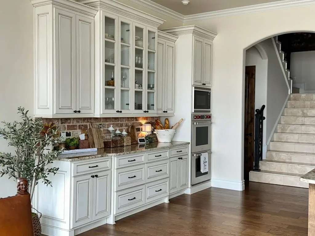 Cabinet Painters in Tyler Tx providing professional refinishing for high-end, detailed white kitchen cabinetry in a luxury open-concept home.