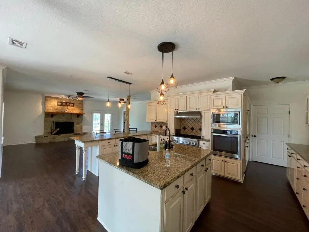 Expert kitchen cabinet and interior painting, showcasing a modern two-tone black and white kitchen design with a feature wall in a high-end Tyler, TX home.
