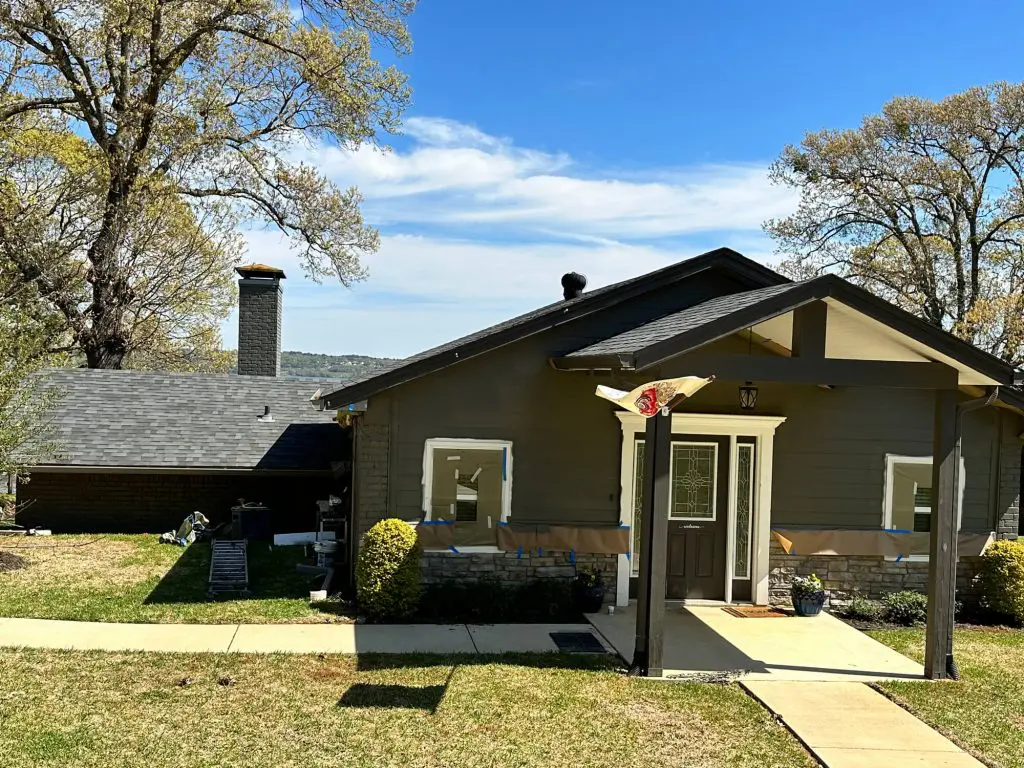 Expert exterior painting transforming a lakeside home with a custom dark gray siding color and crisp white trim in the Tyler, TX area.