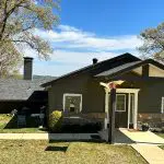 Expert exterior painting transforming a lakeside home with a custom dark gray siding color and crisp white trim in the Tyler, TX area.