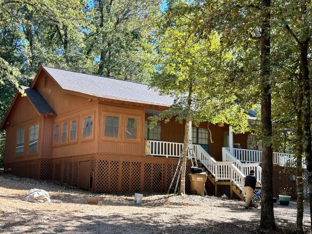 Painters in Tyler Tx specializing in open-concept interior projects, showcasing a custom black fireplace accent, vaulted ceilings, and two-tone kitchen cabinet painting.