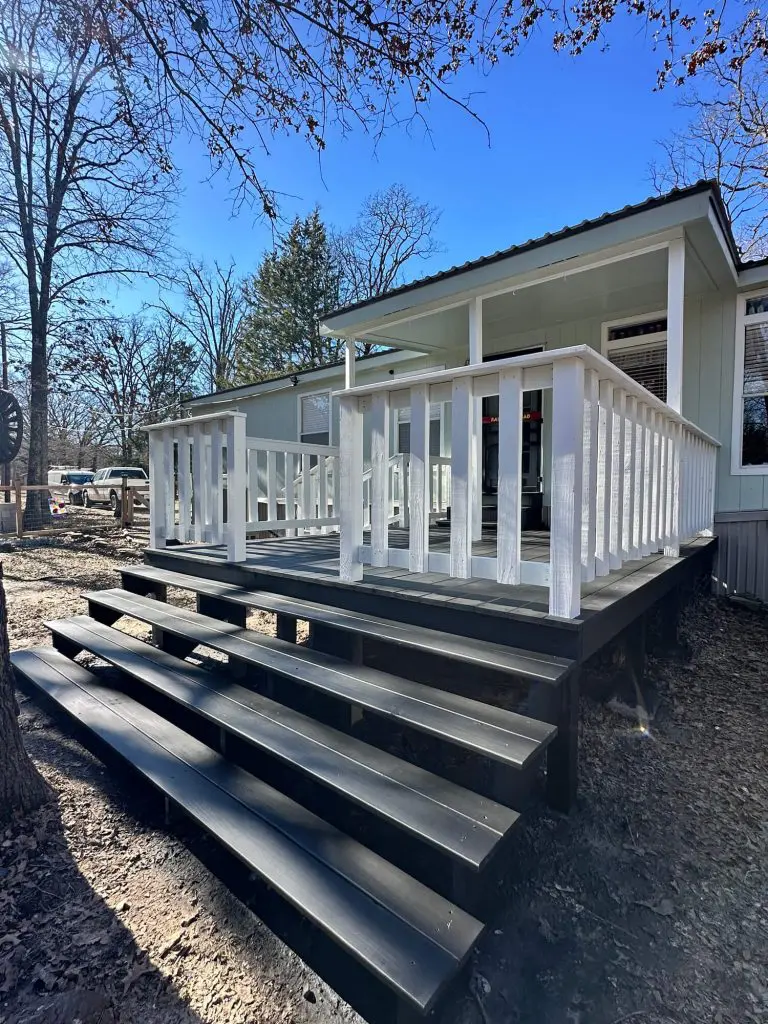 exterior deck painting and wood refinishing, showcasing contrasting white railings and dark gray steps on a wooded residential porch in the Tyler, TX area.