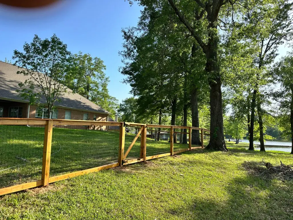Professional fence staining and refinishing on a lakeside property, showcasing durable wood and wire mesh fencing for a luxury home in the Tyler, TX area.