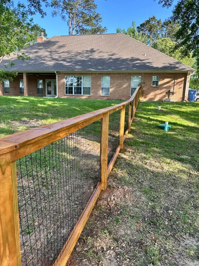 Professional fence staining service on a custom wood and wire mesh backyard fence for a residential home in the Tyler, TX area.