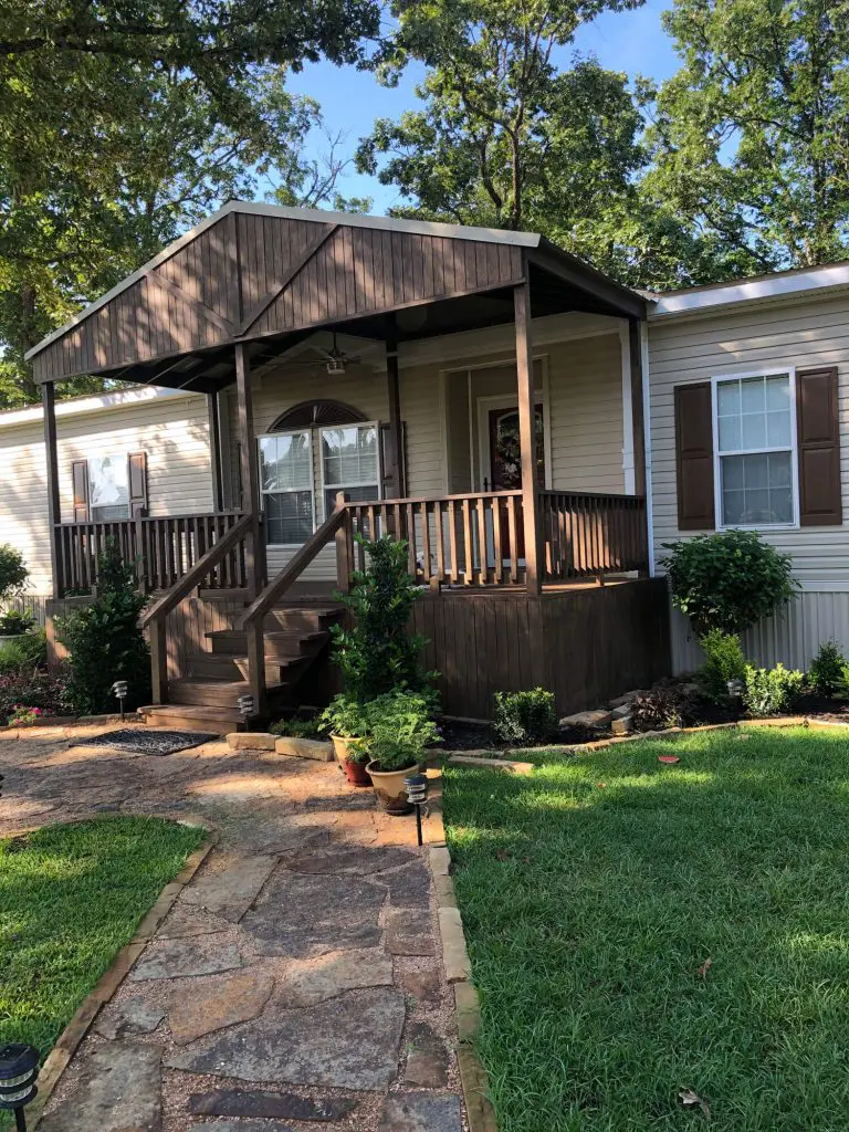 Professional exterior house painting and dark wood deck staining/refinishing on a welcoming lakeside or wooded home in the Tyler, TX area.