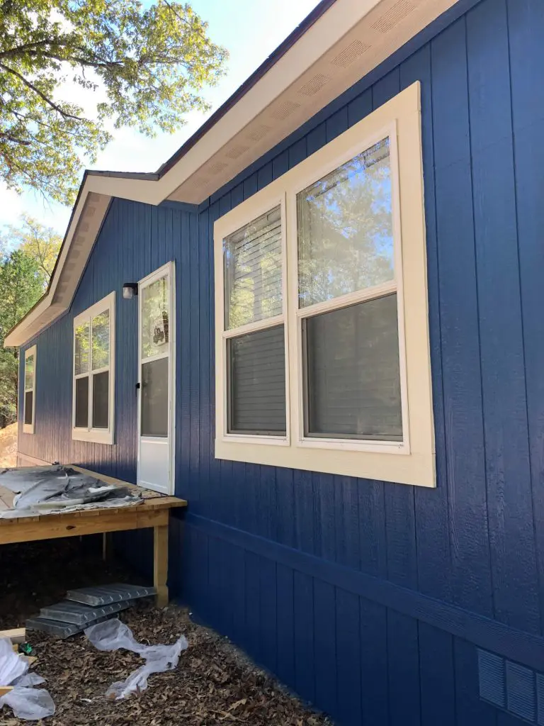Expert exterior siding painting featuring a bold custom blue color and contrasting light trim on a residential or lakeside property in the Tyler, TX area.