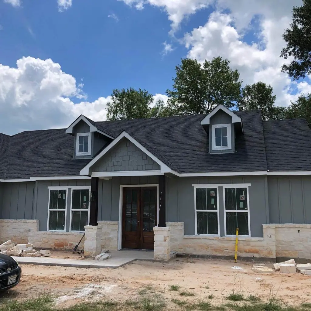 High-quality exterior painting for a new custom residential home, featuring modern gray-green siding and crisp white trim against a stone foundation in the Tyler, TX area.