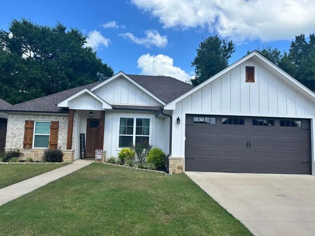 Painters in Bullard, TX Expert exterior house painting featuring crisp white board and batten siding contrasted with a dark brown garage door on a modern farmhouse home