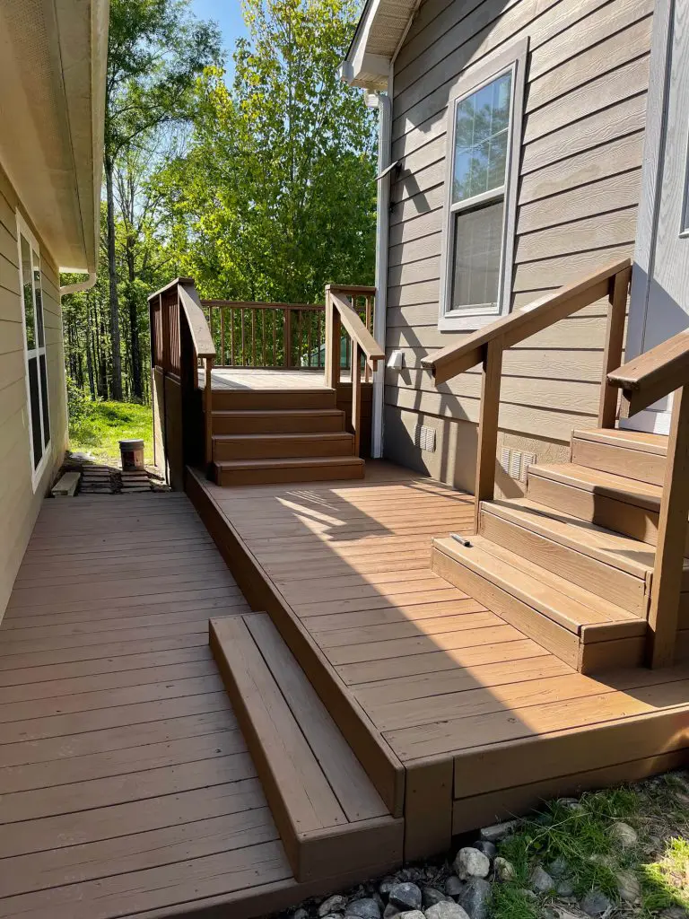 Professional deck staining and finishing service for a multi-level wooden deck and ramp, ensuring a durable finish for a home in the wooded Tyler, TX area.