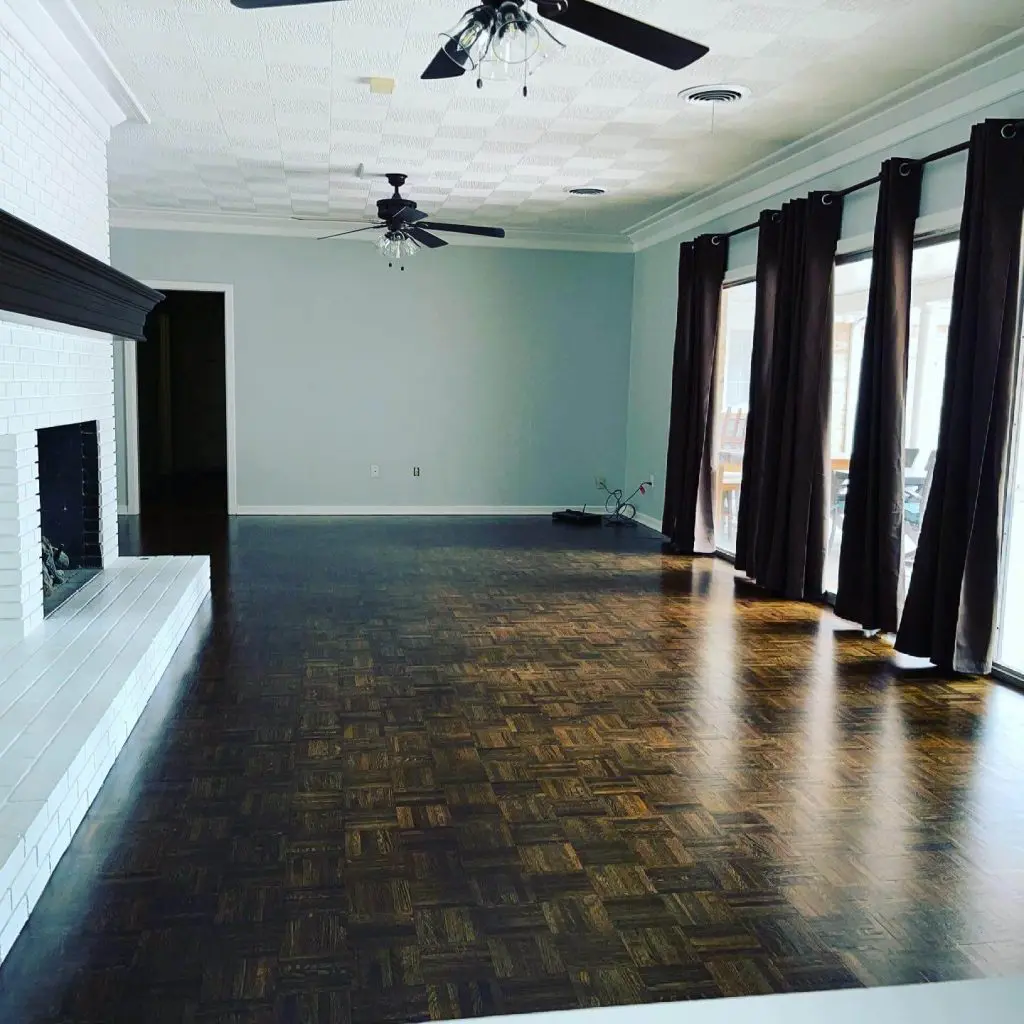 High-quality interior painting of a spacious living room, featuring a custom light wall color, white crown molding, and a freshly painted white brick fireplace in Tyler, TX.