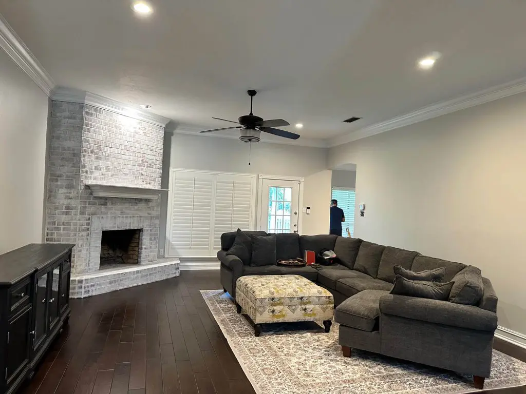 Interior painting of a luxury living room featuring a white-washed brick fireplace and crisp white crown molding by Z&A Custom Painting.