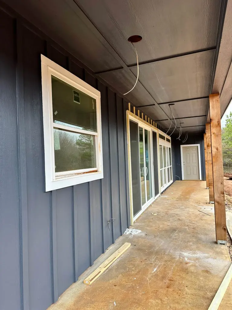 High-quality exterior painting of residential siding and porch soffits, showcasing a modern dark custom color with crisp white window trim in Tyler, TX.