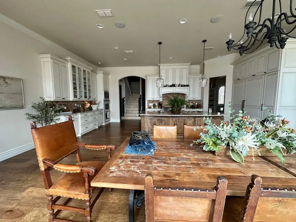 Professional kitchen cabinet painting and refinishing, showcasing extensive white cabinetry and detailed white crown molding in a luxury open-concept home in Tyler, TX.