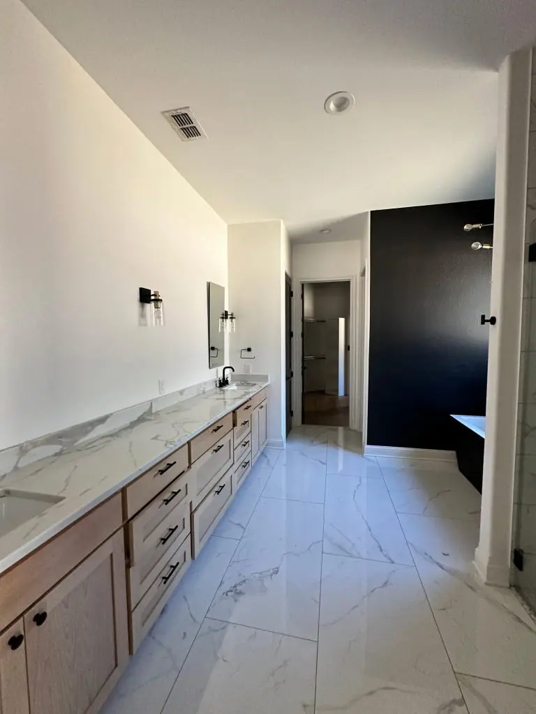 High-end bathroom painting and cabinet refinishing featuring a bold black accent wall, crisp white walls, and modern trim work for a luxury home in Tyler, TX.