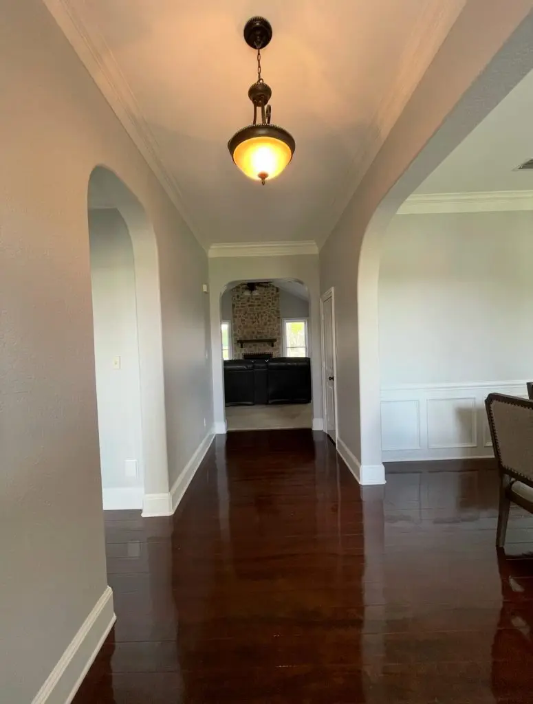Professional interior painting of a luxury arched hallway featuring light gray walls, white crown molding, and high-gloss floors by Z&A Custom Painting.