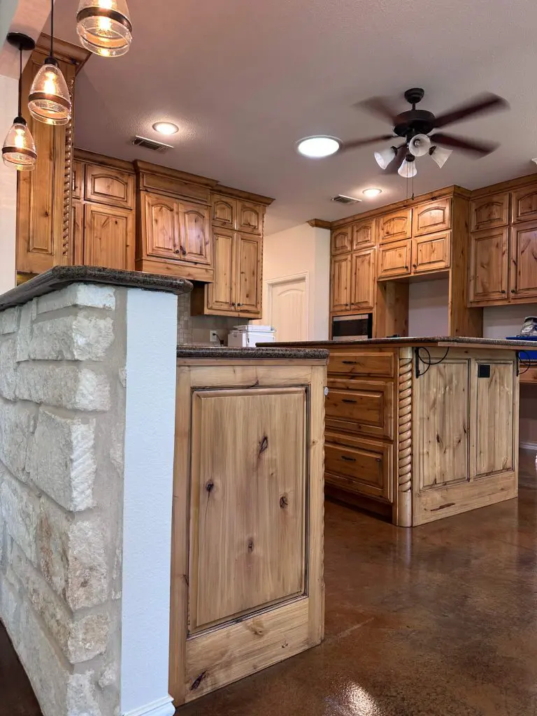 Rustic luxury kitchen with natural knotty pine cabinets and stone accents, highlighting the Cabinet Painting and Refinishing service by Z&A Custom Painting.